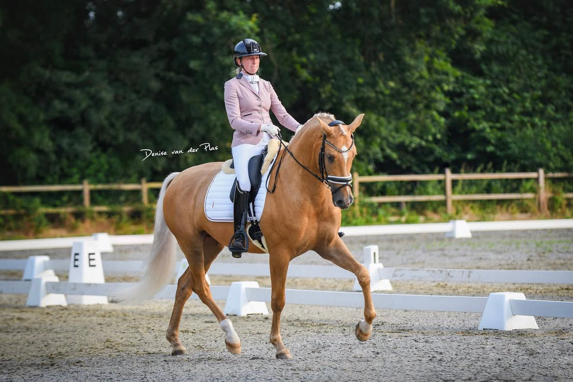 Kirsten Hoogerwerf riding her palomino horse at the regional championships, in a JuulC competition coat