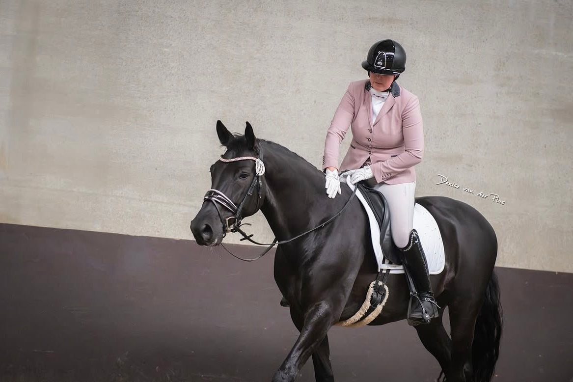 Robin Cornax rewarding her black gelding after their dressage competition, wearing her JuulC show jacket
