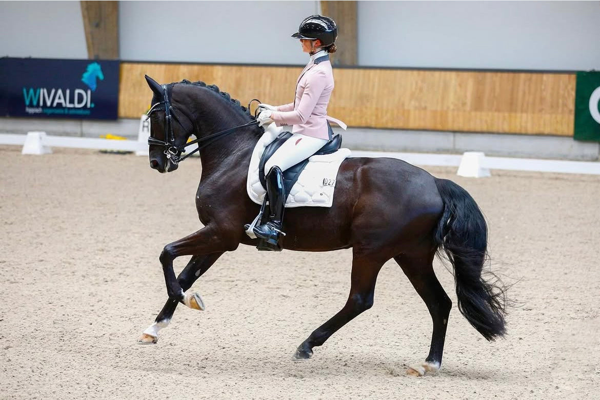 Febe van Zwambagt riding her horse in an extended canter to a Dutch National Titel, wearing her JuulC show jacket