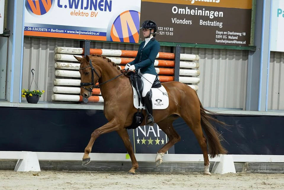 Fleur Vos competing her chestnut in a class for young dressage horses, wearing a JuulC show coat