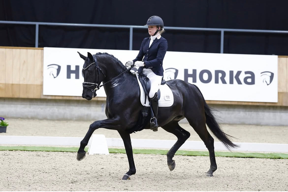 Stephanie Berends riding an extended trot at the Dutch National Championships in a JuulC show coat